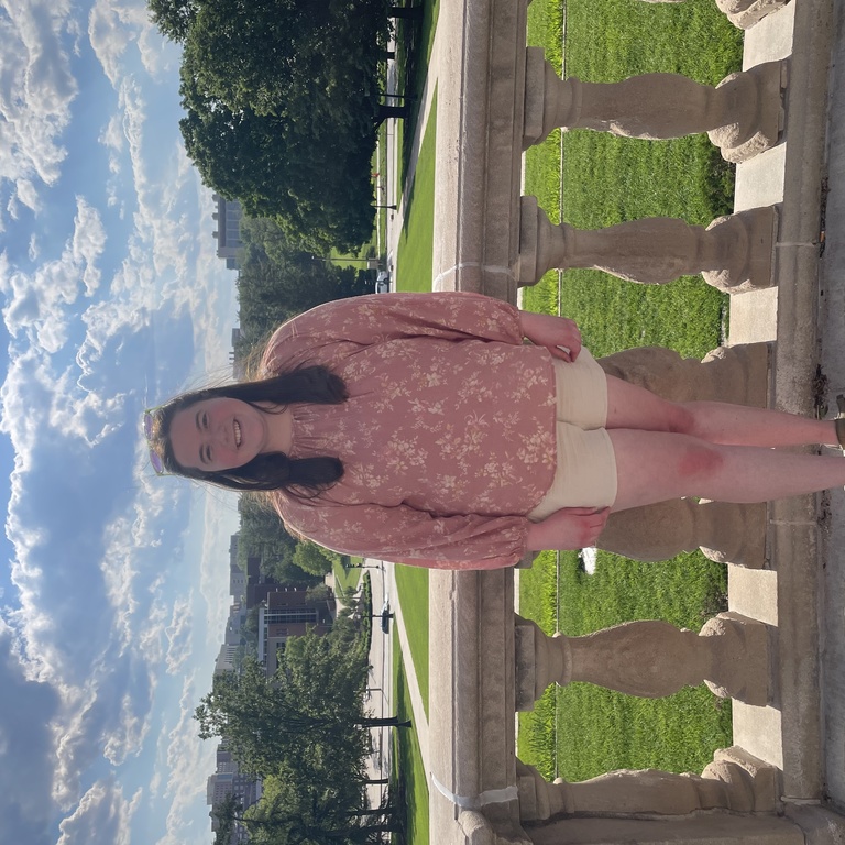 Photo of Jenna standing on a balcony on a sunny day.